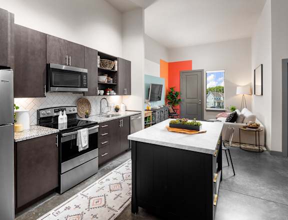 A modern kitchen with a refrigerator, microwave, oven, and sink.