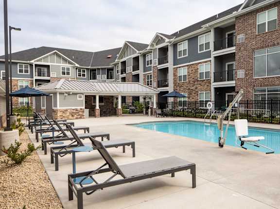 A pool area with sun loungers and a building in the background at Avonlea in Lakeville, MN