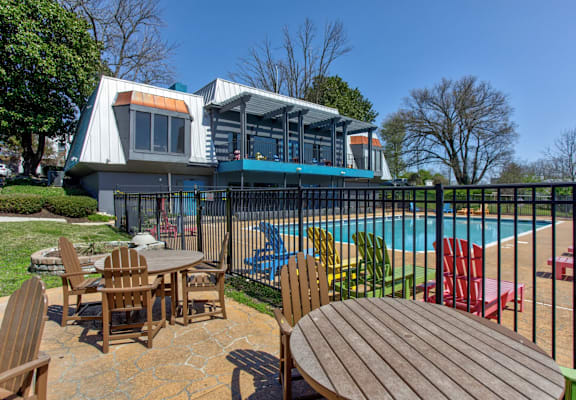 a patio with tables and chairs next to a swimming pool
