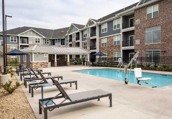A pool area with sun loungers and a building in the background at Avonlea in Lakeville, MN