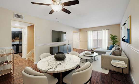 A living room with a white ceiling fan and a round marble table surrounded by chairs.