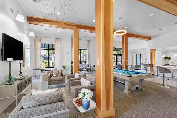 A living room with a pool table and a television.