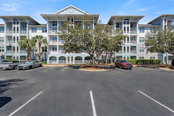 A large white building with a parking lot in front.