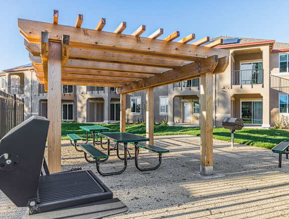 A wooden pergola is over a picnic table.