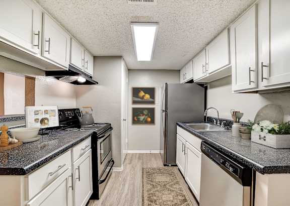 A kitchen with black countertops and white cabinets.