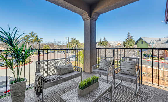 A balcony with a bench, cushions, and a potted plant.