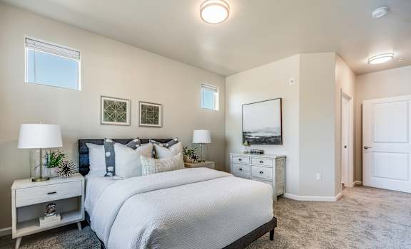 A bedroom with a large bed, nightstand, and a painting on the wall.
