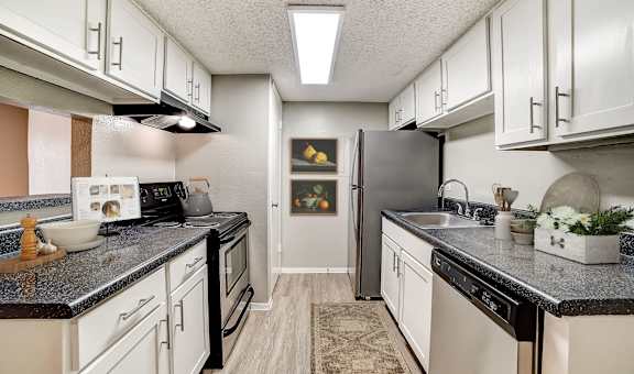 A kitchen with black countertops and white cabinets.