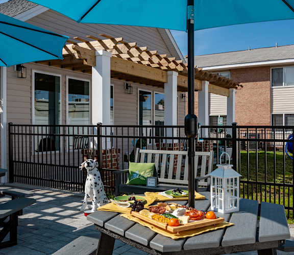 A picnic setup on a patio with a blue umbrella.