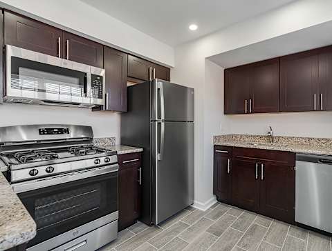 A kitchen with brown cabinets and a black refrigerator. at Chatham Hill, Chatham, New Jersey