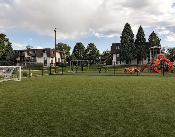 A playground with a red slide and a soccer goal.