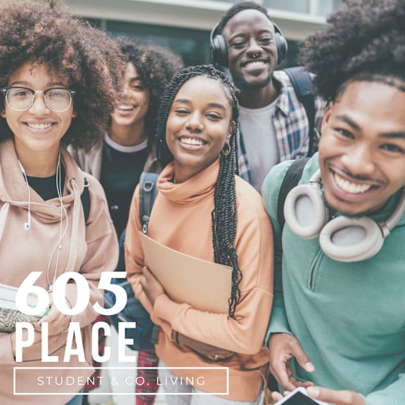 A group of students are standing together, one of them is holding a book.