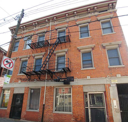 the side of a brick building with windows and a fire escape