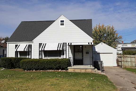 A white house with a black roof and a small porch.