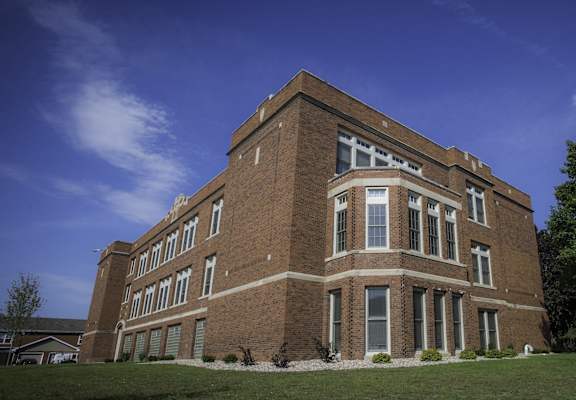 A large red brick building with a flat roof and a large window on the second floor.
