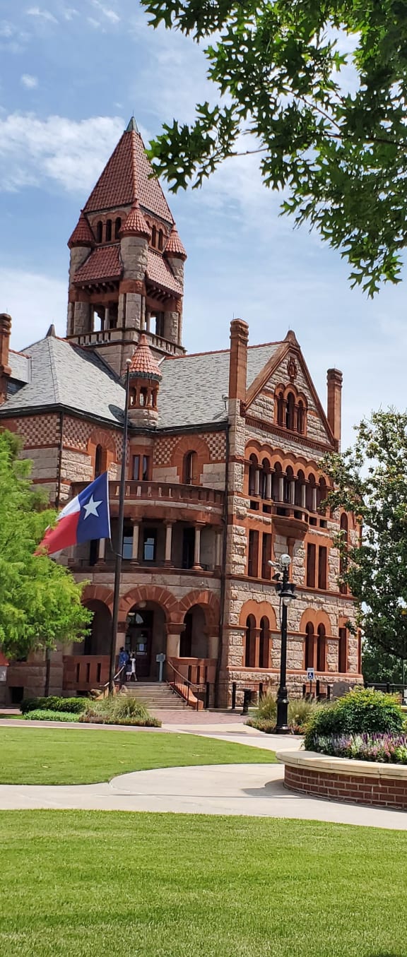 a large brick building with a clock tower and flags on the lawn