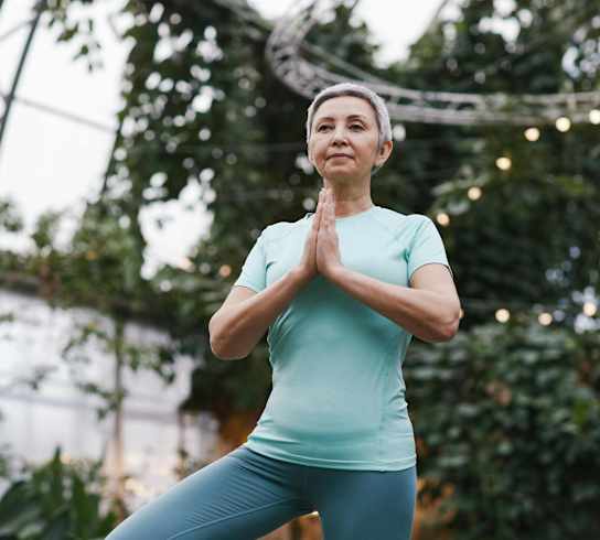 a woman standing in a yoga pose with her hands together
