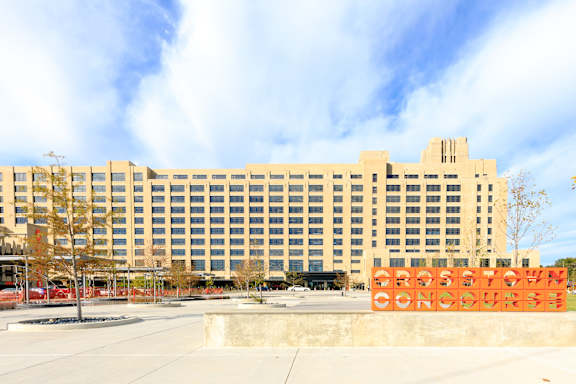 A large building with a sign that says "Grassy Knoll Concourse" in front of it.