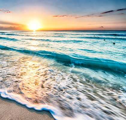 a beach at sunset with the sun setting over the ocean at Copa Triana Apartments, Torrance, CA