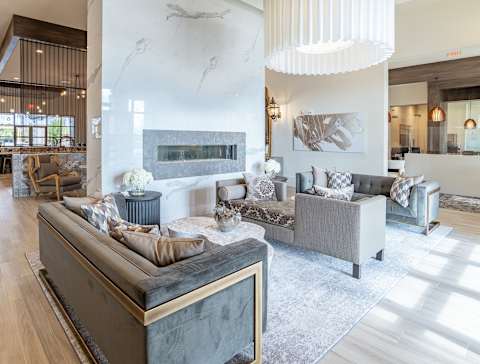 A modern living room with a grey sofa set and a fireplace at Alys Crossing Apartments, Cypress, Texas