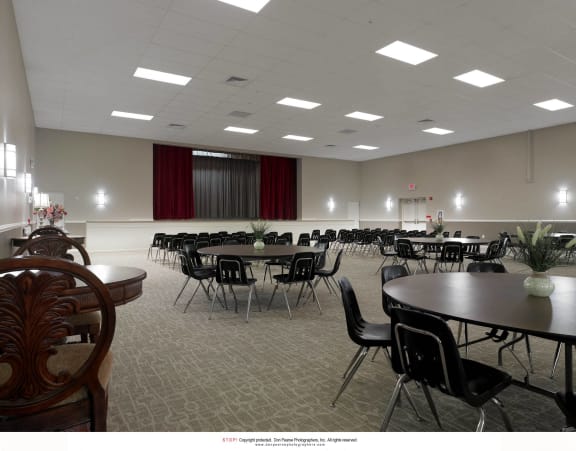 a large room filled with tables and chairs and a projector screen