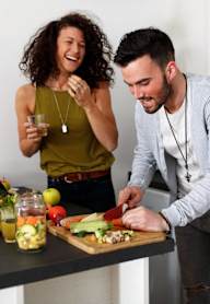 A man and woman are preparing food together in a kitchen.