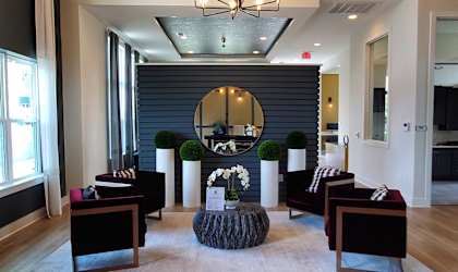 A large mirror hangs on a wall above a table with chairs around it.