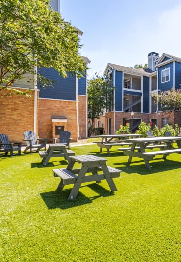 Scenic outdoor picnic area with benches, greenery, and modern apartment views at Gramercy Park Apartments.