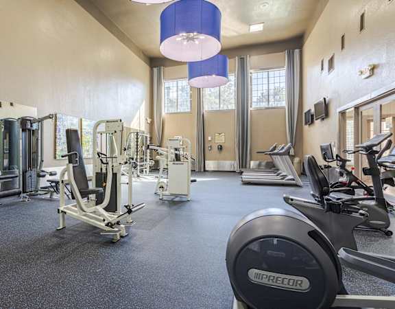 Spacious gym at Gramercy Park Apartments with high ceilings, large windows, and modern equipment.