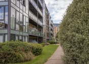 Thumbnail 5 of 6 - the walkway between the buildings is lined with green grass and bushes