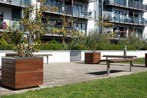 a park with benches and trees in front of an apartment building