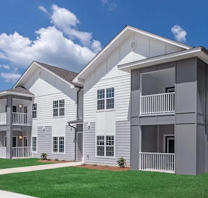A modern two-story apartment building with a balcony on the second floor.