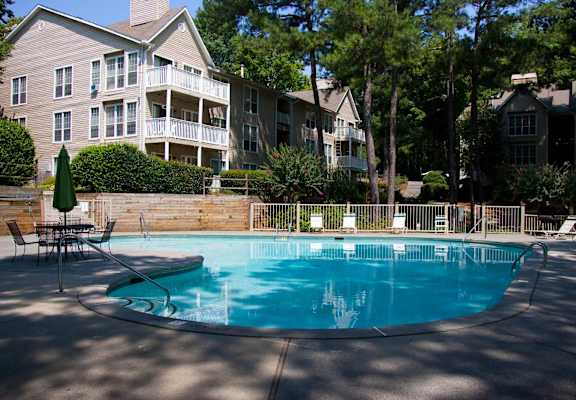 A swimming pool surrounded by a fence and chairs.