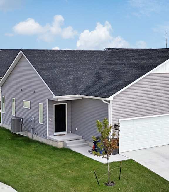 A house with a grey roof and a white garage door.