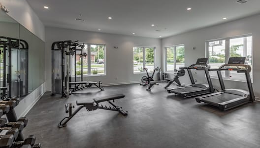 the gym has treadmills and other exercise equipment in a large room with windows