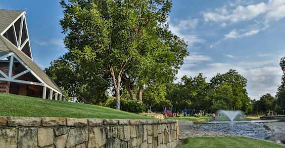 A stone wall borders a water feature in a park.