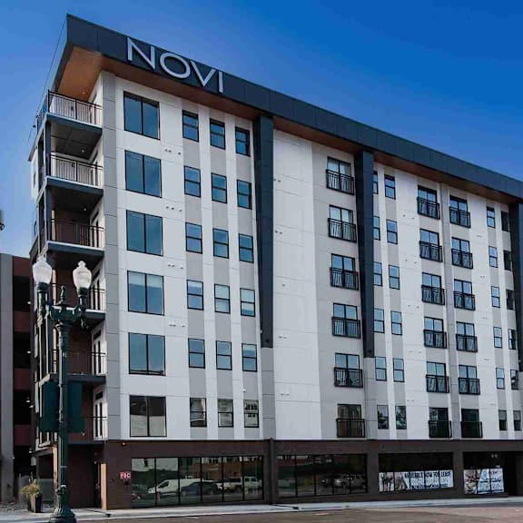 A tall white building with balconies on the upper floors and a red brick building with the word "LOFIS" on it in front.
