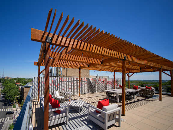 a roof deck with benches and a wooden pergola on top of a building