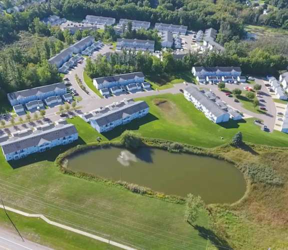 an aerial view of a campus with a pond and buildings