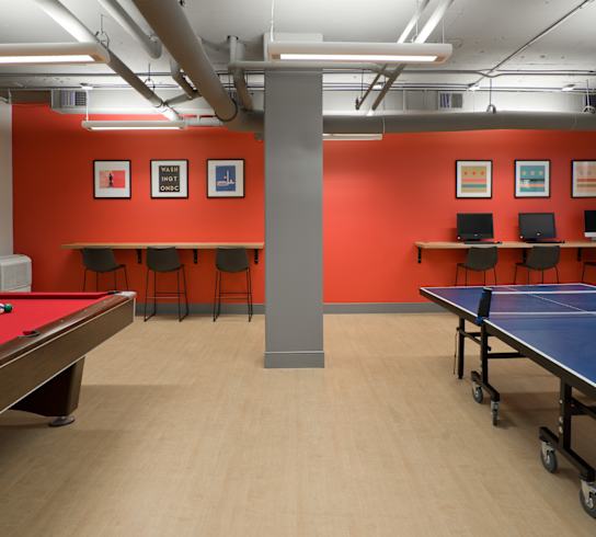 a games room with two ping pong tables and a row of tables and chairs  at 3333 Wisconsin, Washington, DC, 20016