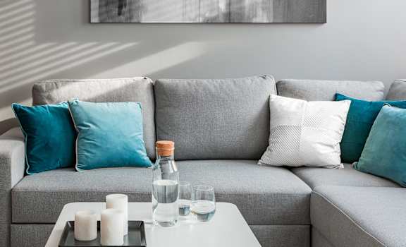 A grey couch with blue and white pillows  at Barcelo at East Cobb Apartments, Marietta