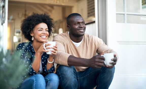 Two people sitting outside, one holding a cup.