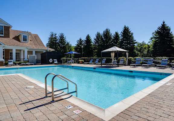 a swimming pool with chairs and a house in the background at The Ledges Apartment Homes, Groton, 06340