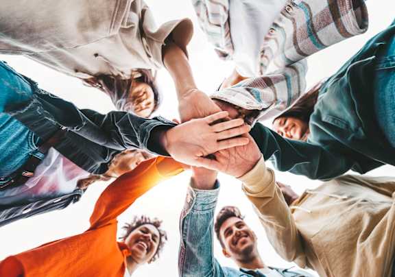 A group of people are seen from above, their hands stacked on top of each other.