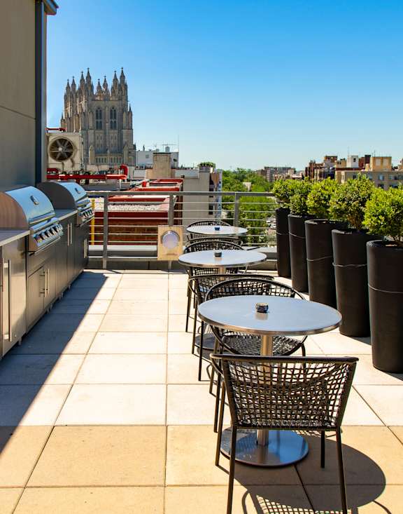 a rooftop patio with tables and chairs and a view of the city