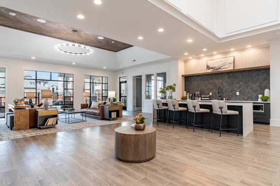A modern living room with a wooden floor and a kitchen area in the background.at The One at Millington, Millington, 38053