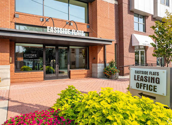 The front of the Eastside Flats leasing office is shown with a sign and flowers.