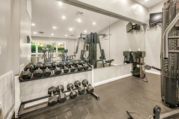 A gym with a variety of equipment including dumbbells and weight machines.
