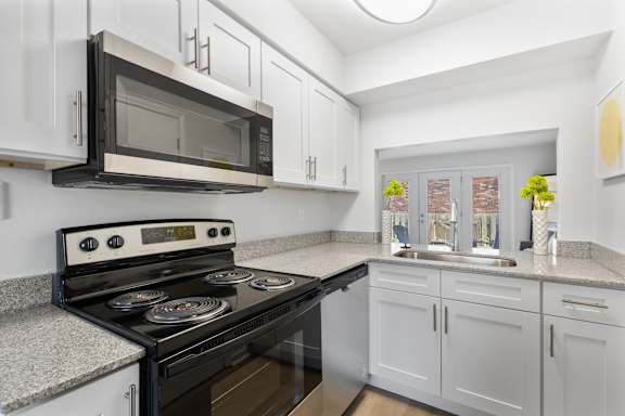 Updated kitchen at Monon Living with stainless steel appliances, granite counters, and stylish cabinetry in a pet-friendly community near the Monon Trail.