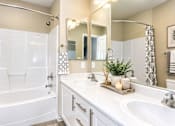 Thumbnail 6 of 8 - A white bathroom with a large mirror and a bathtub.